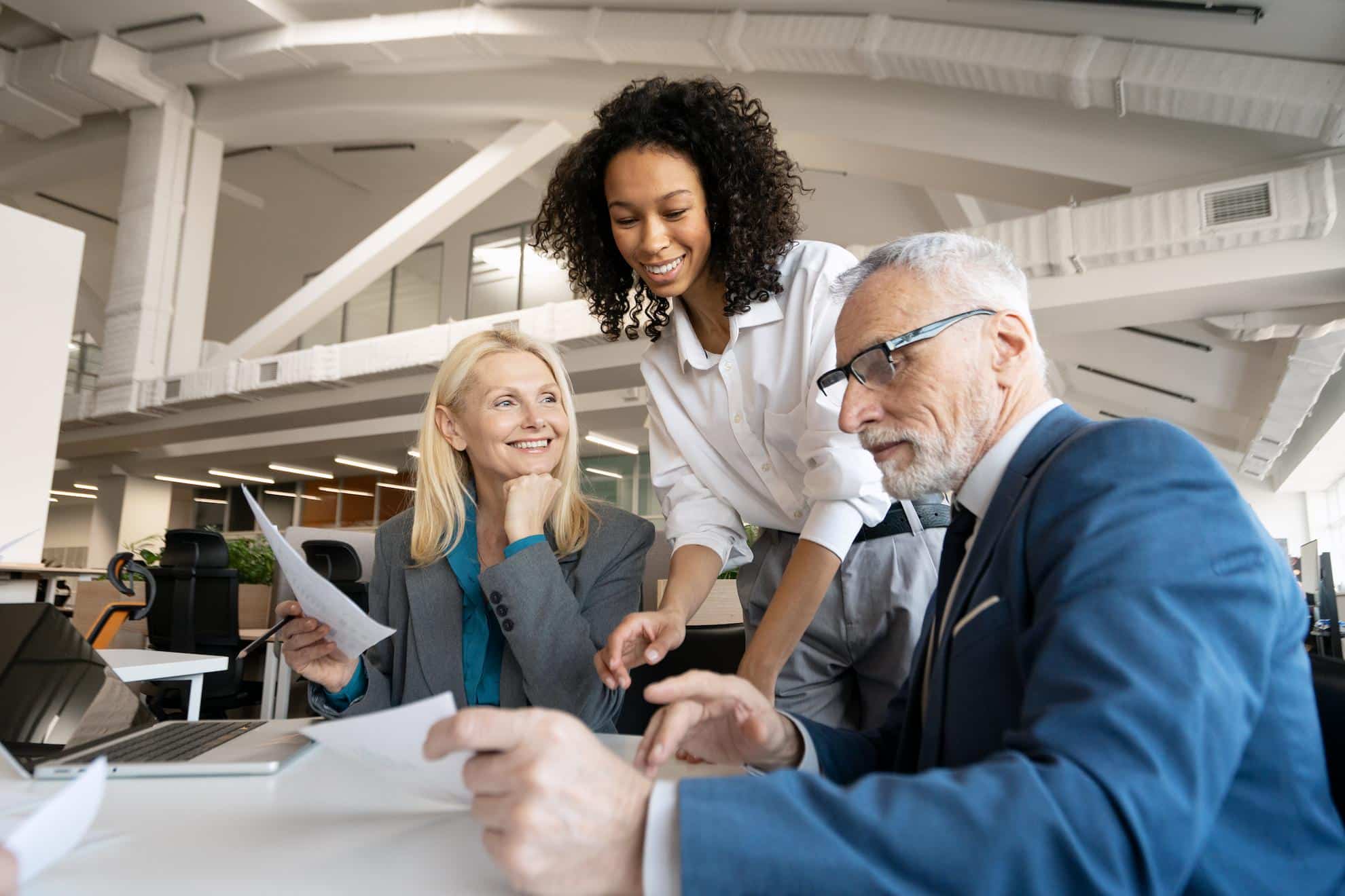 Three professionals discussing business documents in a modern office, illustrating collaboration on Articles of Association and strategic tax planning.