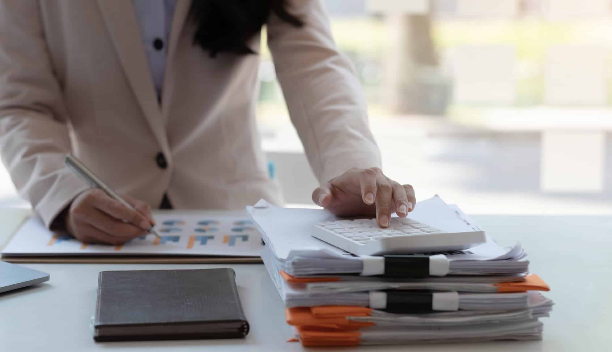 Business professional reviewing financial documents and calculating tax compliance.