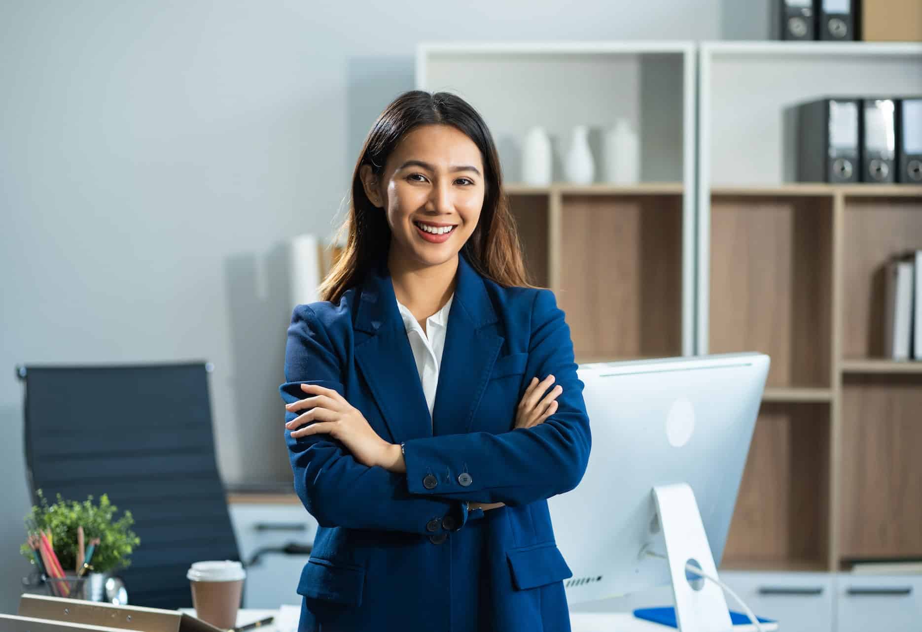 A confident businesswoman with her arms crossed in her neat and tidy office in the UAE.