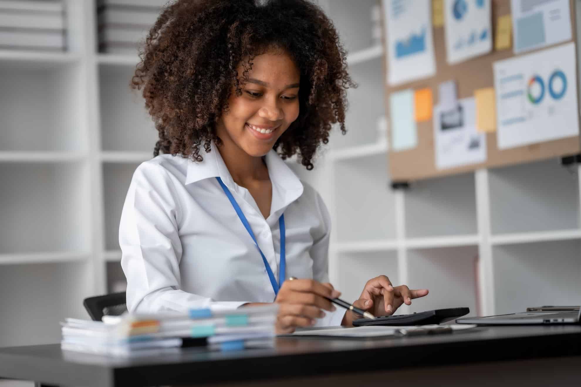 UAE bookkeeper reviewing financial documents and using a calculator to ensure accurate business bookkeeping and compliance.