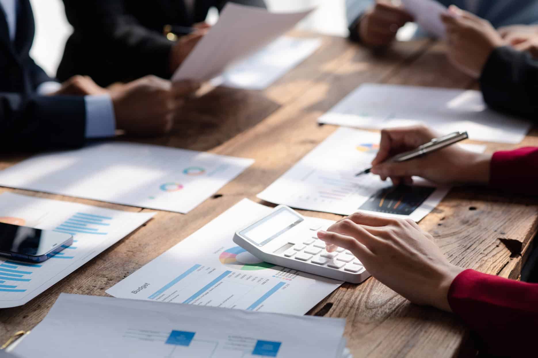 Finance team preparing a corporate tax expense add-back schedule with reports and calculator in the UAE.