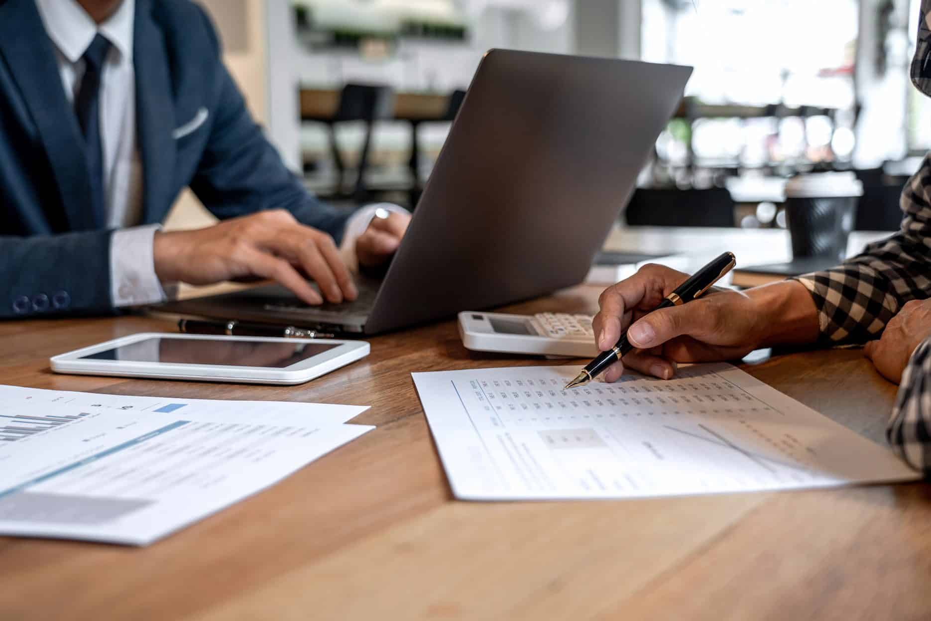 Business professionals reviewing expense records, calculator, and laptop during cost classification in the UAE.