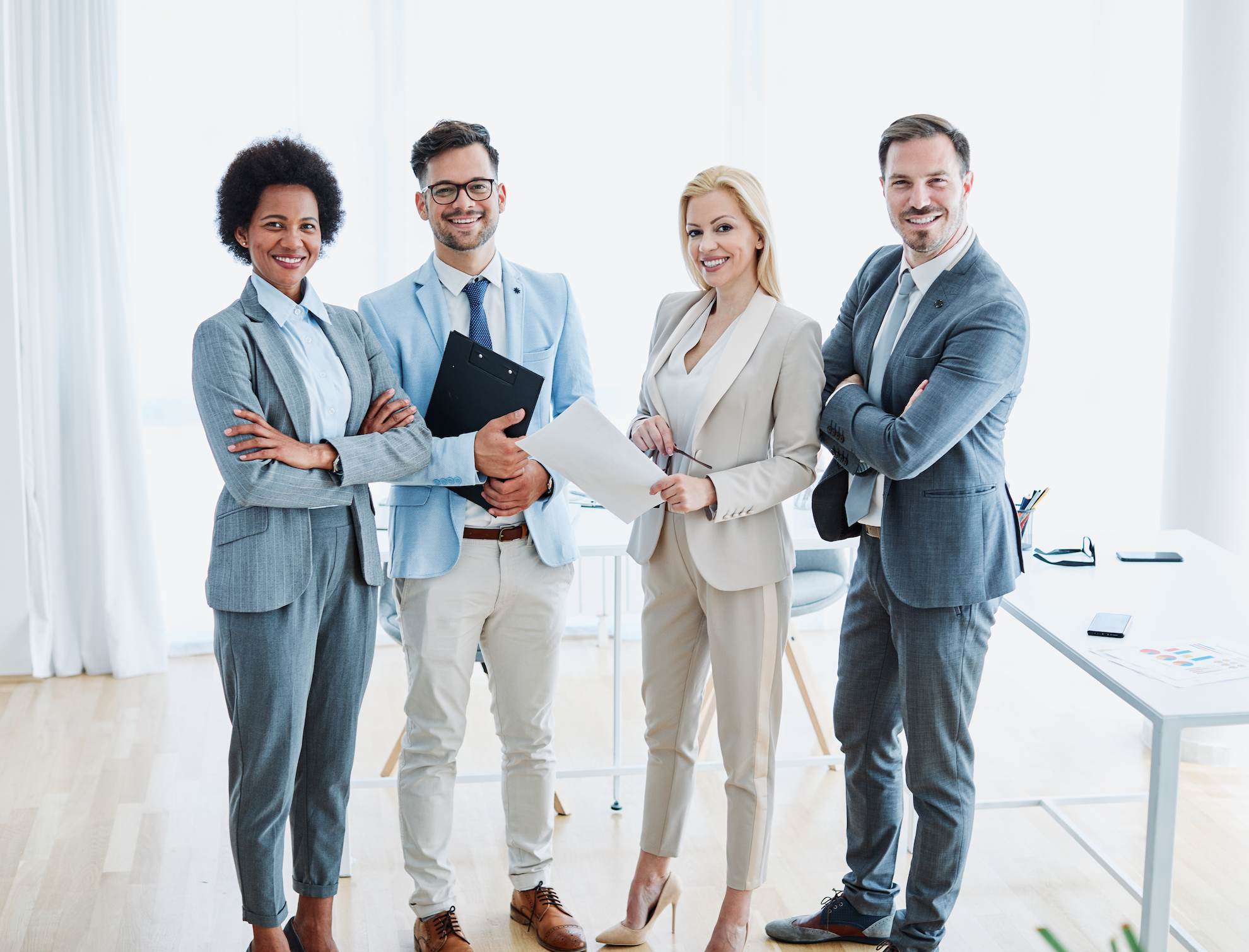 Four well-dressed tax agents posing for a group photo in their office.