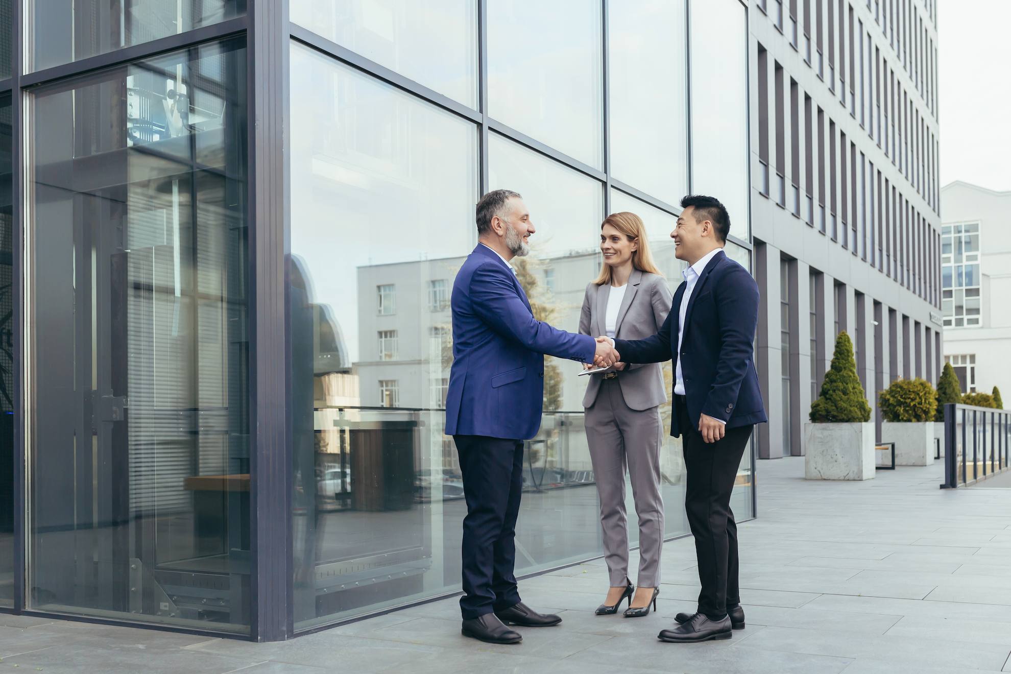 Business professionals shaking hands outside a modern commercial building, symbolising commercial property transactions and VAT compliance in the UAE.